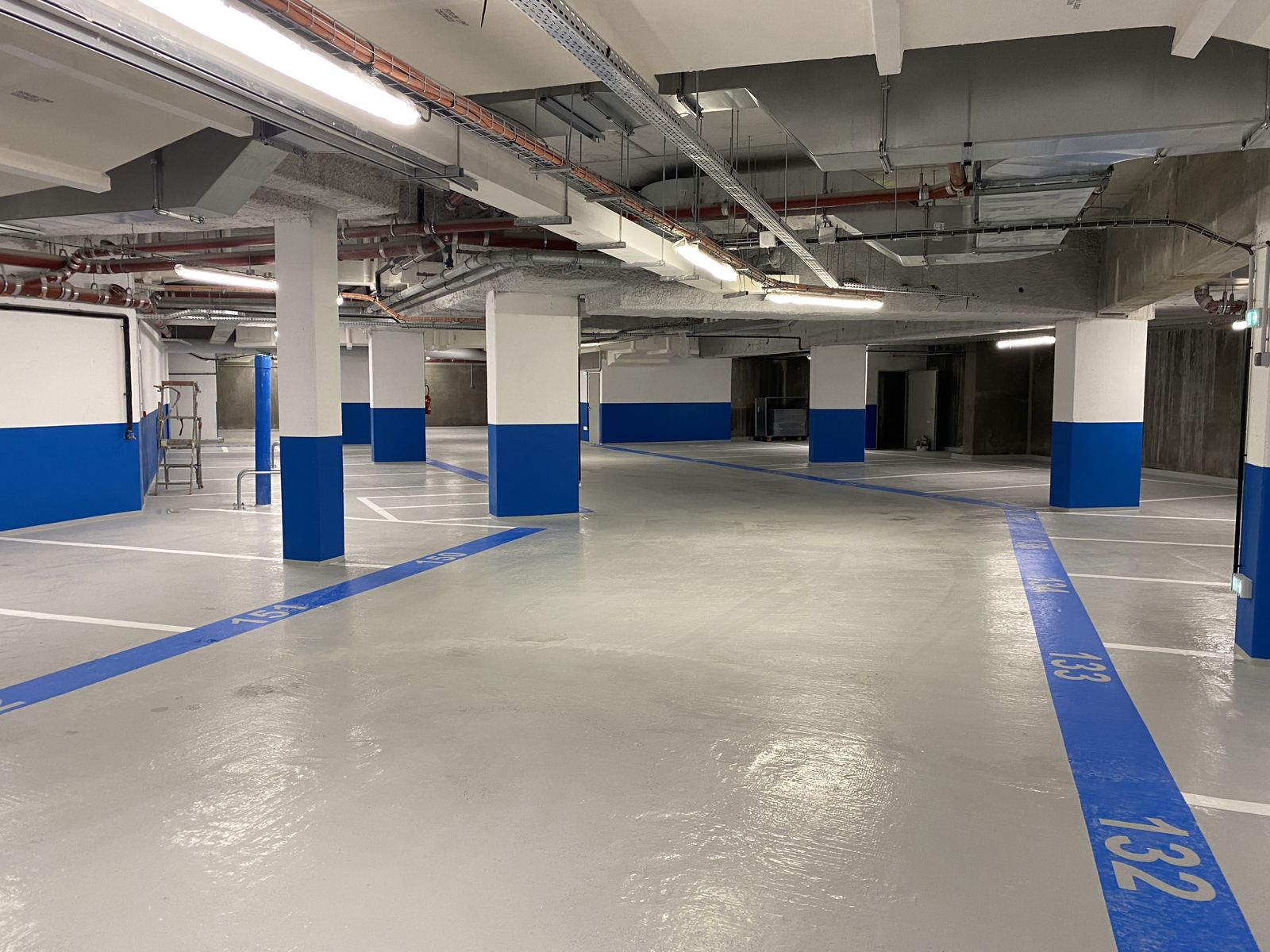 Parking rénové — sol résiné gris et numérotation bleue des places
